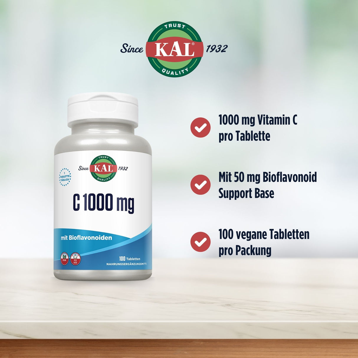 Das Bild zeigt eine Flasche KAL C 1000 mg mit Bioflavonoiden auf einem Tisch. Auf der Flasche steht "1000 mg Vitamin C pro Tablette, mit 50 mg Bioflavonoid Support Base, 100 vegane Tabletten pro Packung". Im Hintergrund ist ein unscharfer, heller Raum zu sehen.