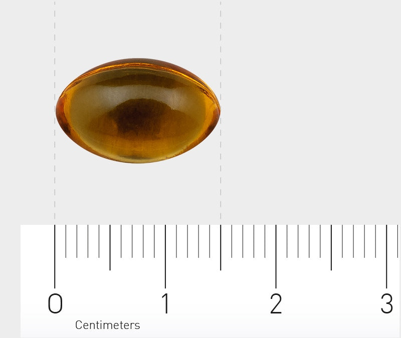 Eine gelbe, ovale Kapsel liegt auf einem weißen Hintergrund. Unter der Kapsel befindet sich ein Lineal, das in Zentimetern skaliert ist. Die Kapsel hat etwa einen Durchmesser von 2 Zentimetern. Die Umgebung ist schlicht und minimalistisch.