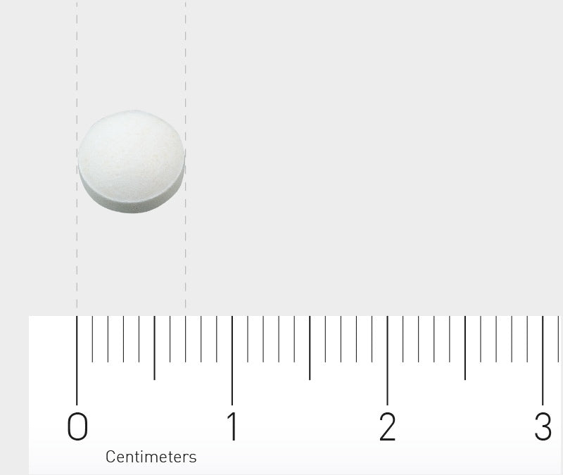 Eine weiße Tablette liegt auf einem Lineal, das in Zentimetern skaliert ist. Die Tablette befindet sich zwischen den Markierungen 0 und 1 Zentimeter. Der Hintergrund ist hellgrau.