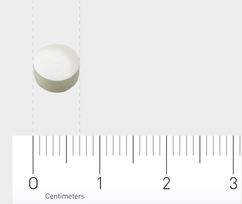 Ein kleines, rundes, weißes Objekt, das wie eine Tablette aussieht, liegt auf einer weißen Oberfläche. Unterhalb des Objekts ist ein Lineal mit Zentimeter-Markierungen zu sehen, das die Größe des Objekts zeigt. Der Hintergrund ist einheitlich hellgrau.