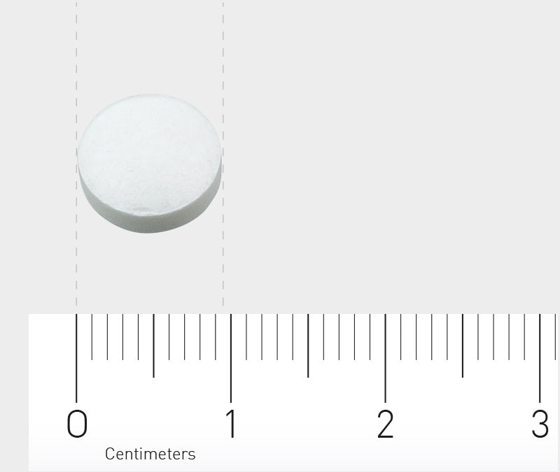 Das Bild zeigt eine einzelne weiße Tablette auf einem hellgrauen Hintergrund. Unterhalb der Tablette befindet sich ein Lineal, das in Zentimetern skaliert ist, von 0 bis 3 cm, um die Größe der Tablette zu verdeutlichen.