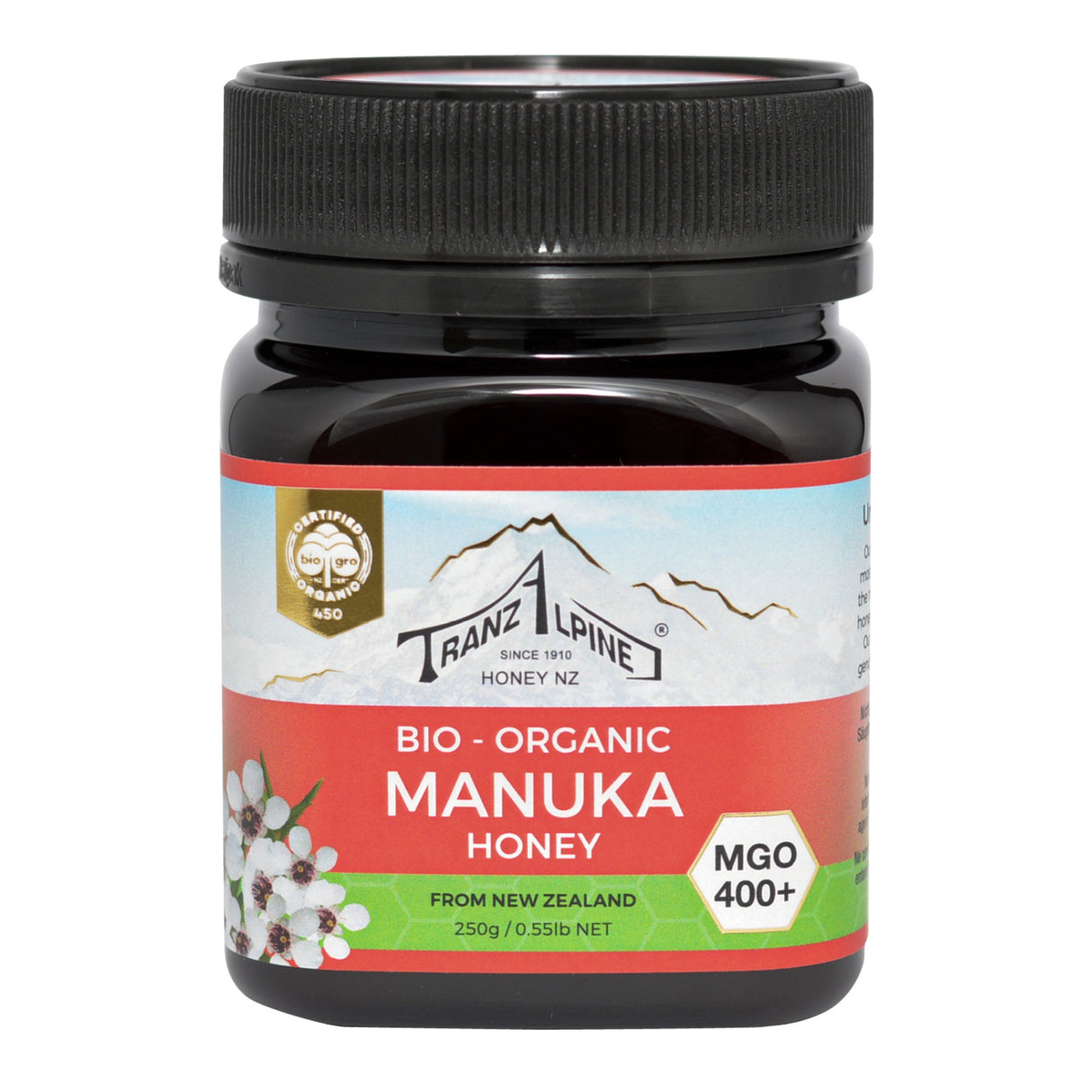 Ein Glas Bio-Manuka-Honig der Marke TranzAlpine ist abgebildet. Das Etikett zeigt ein Bergmotiv und die Aufschrift 'Bio-Organic Manuka Honey MGO 400+ aus Neuseeland'. Der Honig ist in einem dunklen Glas mit schwarzem Deckel verpackt.
