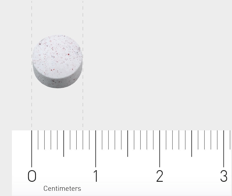 Das Bild zeigt eine weiße Tablette mit roten Flecken, die auf einem Lineal liegt. Das Lineal hat eine Skala in Zentimetern und Millimetern. Die Tablette liegt bei etwa 1,5 Zentimetern auf der Skala.