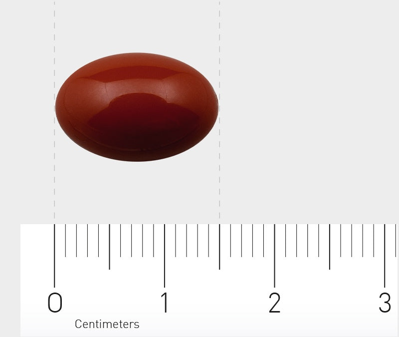 Rote, ovale Tablette auf einem Lineal mit Zentimetermarkierungen.