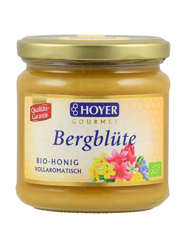 Ein Glas Hoyer Gourmet Bio-Honig 'Bergblüte' mit goldfarbenem Deckel und buntem Etikett mit Blumenmotiv.