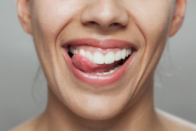 Close-up of a cheerful woman licking her lips, highlighting dental health and joy