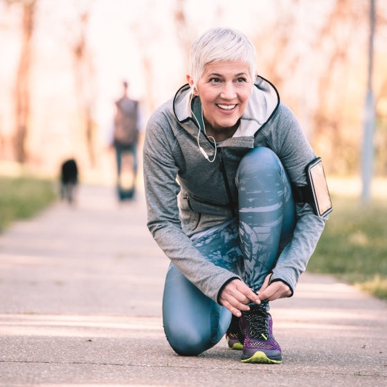 Beautiful woman with gray hair in the early sixties exercising in public park