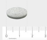 Ein einzelnes, ovales, graues Tablett auf einem weißen Hintergrund. Darunter befindet sich ein Lineal in Zentimetern, das die Größe der Tablette anzeigt. Die Tablette ist etwa 1,5 cm lang.