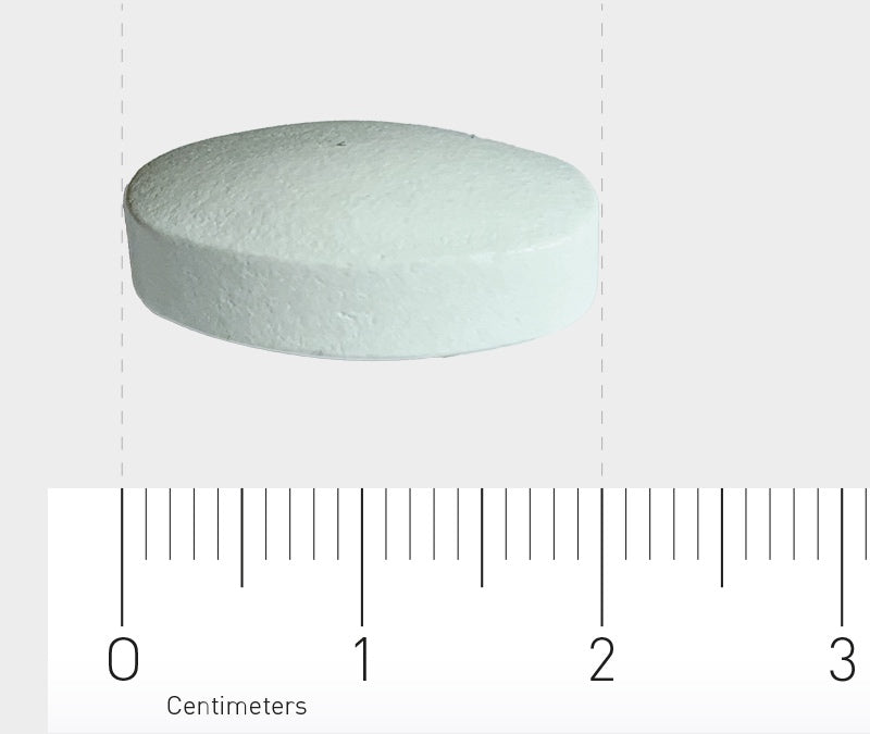 Eine weiße, runde Tablette liegt auf einer Oberfläche. Unterhalb der Tablette befindet sich ein Lineal mit Zentimetermarkierungen, das die Größe der Tablette zeigt. Die Tablette hat einen Durchmesser von etwa 1,5 cm.