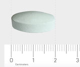 Eine weiße, runde Tablette liegt auf einer Oberfläche. Unterhalb der Tablette befindet sich ein Lineal mit Zentimetermarkierungen, das die Größe der Tablette zeigt. Die Tablette hat einen Durchmesser von etwa 1,5 cm.