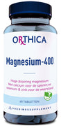 Ein Glasbehälter mit dunkelblauem Deckel, beschriftet mit 'Orthica Magnesium-400'. Enthält 60 Tabletten. Text auf Niederländisch: 'Hoge dosering magnesium. Met calcium voor de spieren en selenium & zink voor de weerstand.' Vegan-Logo.