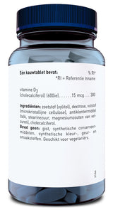 Die Abbildung zeigt ein transparentes Glas mit blauen Kautabletten und einem blauen Schraubverschluss. Auf dem weißen Etikett sind die Inhaltsstoffe und die Nährwertangaben der Tabletten auf Niederländisch aufgedruckt. Die Kautabletten enthalten Vitamin D3 (Cholecalciferol) mit 600 IE pro Tablette. Weitere Inhaltsstoffe sind Xylitol, Dextrose, mikrokristalline Cellulose, Talk, Stearinsäure, Magnesiumsalze von Fettsäuren und Cholecalciferol. Das Produkt ist frei von Hefe, synthetischen Konservierungsstoffen 