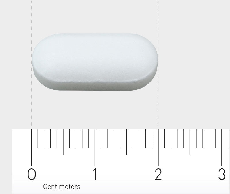 Das Bild zeigt eine weiße, ovale Tablette, die auf einem Lineal liegt. Das Lineal misst in Zentimetern und zeigt, dass die Tablette etwa 2 Zentimeter lang ist. Der Hintergrund ist grau.