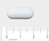 Das Bild zeigt eine weiße, ovale Tablette, die auf einem Lineal liegt. Das Lineal misst in Zentimetern und zeigt, dass die Tablette etwa 2 Zentimeter lang ist. Der Hintergrund ist grau.