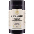 Ein Behälter mit der Aufschrift "Wilde Blaubeeren Pulver". Das Etikett zeigt, dass es sich um ein gentechnikfreies, glutenfreies und veganes Produkt handelt. Der Behälter hat ein Fassungsvermögen von 250 g und ist als Nahrungsergänzungsmittel gekennzeichnet. Das Design ist schlicht und informativ, mit einem goldenen Logo oben auf dem Etikett.