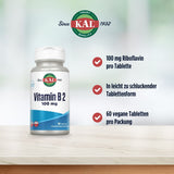 Eine Flasche Vitamin B2 von KAL steht auf einem Tisch. Auf der rechten Seite sind drei Vorteile aufgelistet: 100 mg Riboflavin pro Tablette, leicht zu schluckende Tablettenform, 60 vegane Tabletten pro Packung. Im Hintergrund ist ein verschwommener grüner Hintergrund zu sehen.