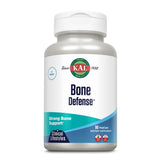 Eine weiße Plastikflasche mit einem Schraubverschluss ist abgebildet. Auf der Flasche steht "KAL Bone Defense" mit dem Hinweis auf starke Knochengesundheit. Die Flasche enthält 90 vegetarische Kapseln. Das Etikett ist in Blau und Grün gestaltet.