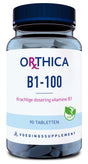 Das Bild zeigt eine Verpackung von Nahrungsergänzungsmitteln der Marke Orthica. Auf der Vorderseite steht 'B1-100' und 'Krachtige dosering vitamine B1'. Es enthält 90 Tabletten und ist als vegan gekennzeichnet. Die Verpackung ist blau und weiß.