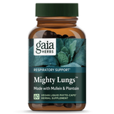 Das Bild zeigt eine braune Flasche mit grünem Schraubverschluss, die das Produkt "Mighty Lungs" von Gaia Herbs enthält. Auf dem Etikett steht "Respiratory Support" und es wird angegeben, dass das Produkt mit Königskerze und Wegerich hergestellt ist. Es sind 60 vegane Flüssigkapseln enthalten. Die Flasche ist vor einem Hintergrund mit grünen Blättern abgebildet.