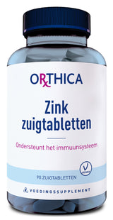 Eine Flasche mit blauen Zink-Zuigtabletten von Orthica. Auf dem Etikett steht: 'Zink zuigtabletten, Ondersteunt het immuunsysteem, 90 zuigtabletten, Voedingssupplement'. Das Etikett ist hauptsächlich weiß mit blauen und violetten Akzenten. Die Flasche hat einen dunkelblauen Deckel.