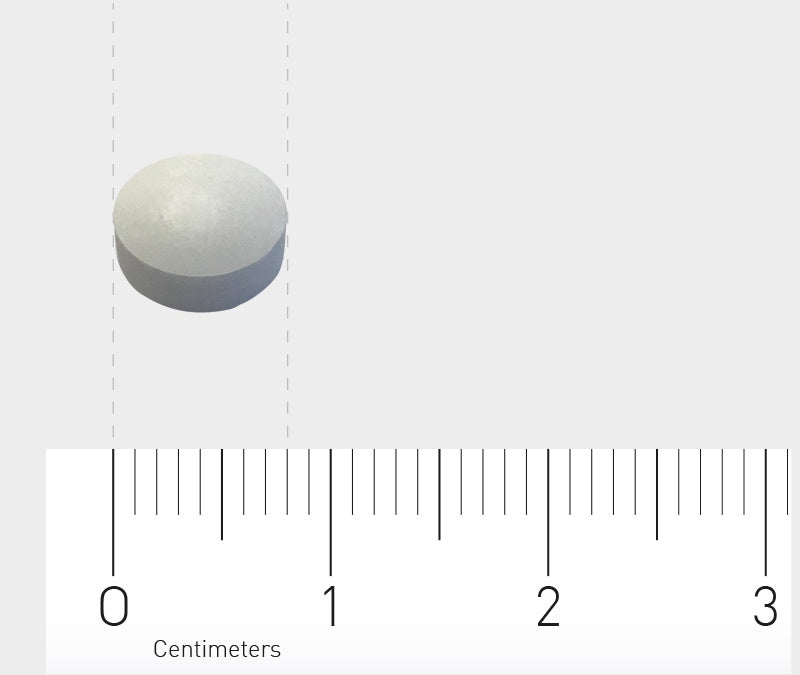 Eine weiße runde Tablette liegt auf einem weißen Hintergrund neben einem Lineal, das in Zentimetern skaliert ist. Die Tablette hat einen Durchmesser von etwa einem Zentimeter. Das Lineal zeigt eine Skala von 0 bis 3 Zentimetern.