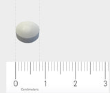 Eine weiße runde Tablette liegt auf einem weißen Hintergrund neben einem Lineal, das in Zentimetern skaliert ist. Die Tablette hat einen Durchmesser von etwa einem Zentimeter. Das Lineal zeigt eine Skala von 0 bis 3 Zentimetern.