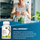 Eine Frau in einem gestreiften T-Shirt steht in einer modernen Küche und fügt Bananenstücke in einen Mixer, der mit Spinat gefüllt ist. Vorne im Bild ist eine Packung "Cell Defense" Nahrungsergänzungsmittel zu sehen. Der Text beschreibt die Vorteile des Produkts als eine Kombination aus moderner Wissenschaft und traditioneller chinesischer Phytotherapie.