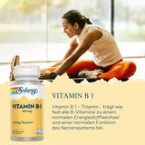 Frau dehnt sich auf Boden, daneben Vitamin B1-Flasche von Solaray. Text beschreibt Vorteile von Vitamin B1 für Energiestoffwechsel und Nervensystem.