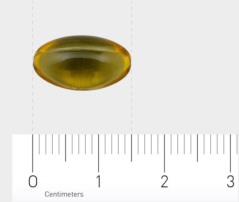 Ein einzelnes, gelbes, ovales Gelkapsel-Pill auf einem weißen Hintergrund mit einem Maßstab im Vordergrund, der Zentimeter anzeigt. Die Kapsel ist transparent und leicht glänzend. Der Maßstab zeigt, dass die Kapsel etwa 2 Zentimeter lang ist.