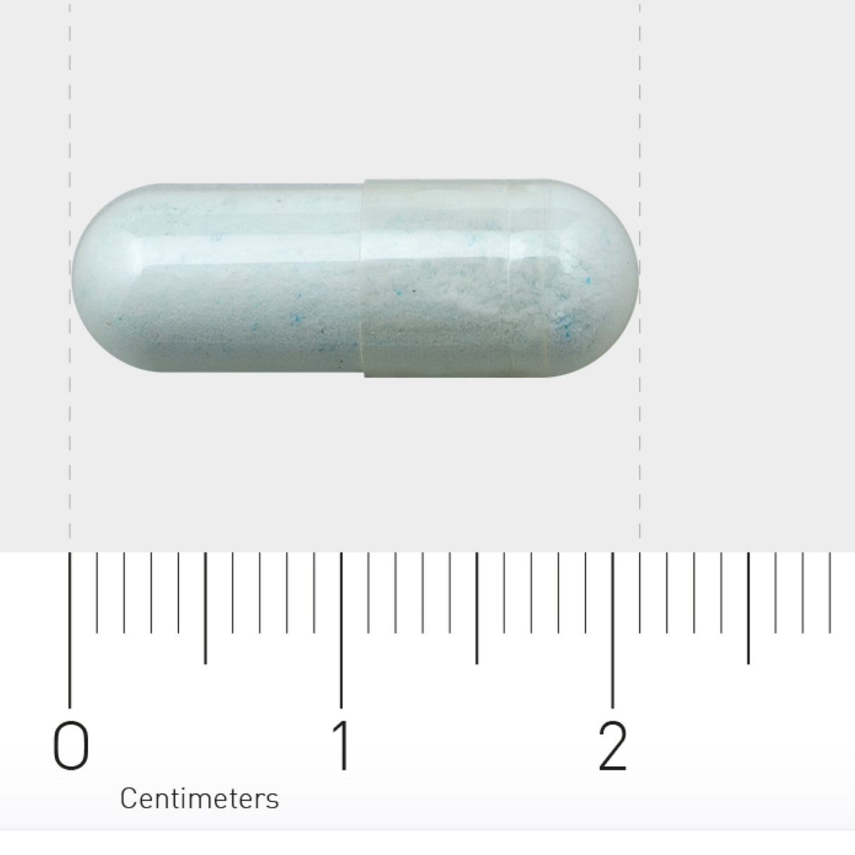 Das Bild zeigt eine weiße Kapsel auf einem Lineal mit Zentimeterangaben. Die Kapsel liegt horizontal und misst etwa 2 Zentimeter. Der Hintergrund ist neutral, sodass der Fokus auf der Kapsel liegt.