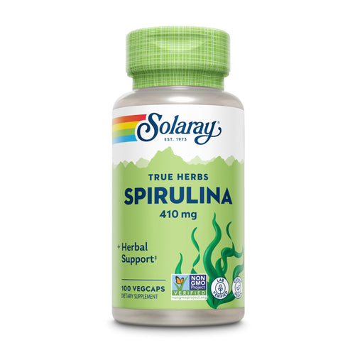 Das Bild zeigt eine Plastikflasche mit grüner Kappe, die Spirulina-Kapseln von Solaray enthält. Auf dem Etikett steht 'True Herbs Spirulina 410 mg', zusammen mit 'Herbal Support', '100 Vegcaps', und mehreren Prüfsiegeln. Die Flasche hat ein grünes Design mit Algen-Motiv.