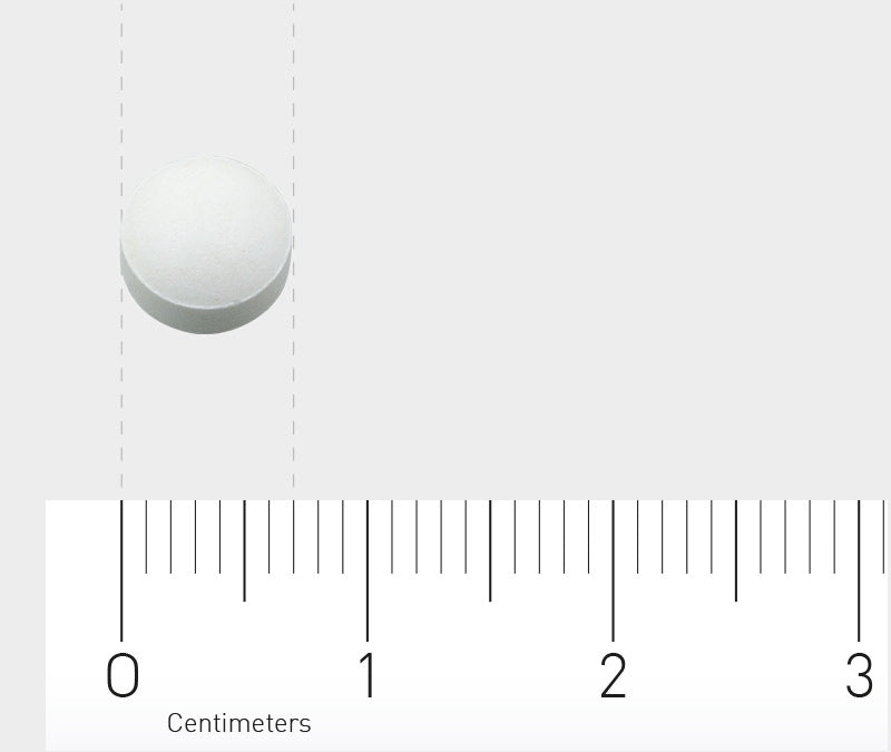 Eine weiße Tablette liegt auf einer grauen Oberfläche. Darunter ist ein Lineal mit Zentimeter-Einteilung zu sehen, das die Größe der Tablette verdeutlicht.