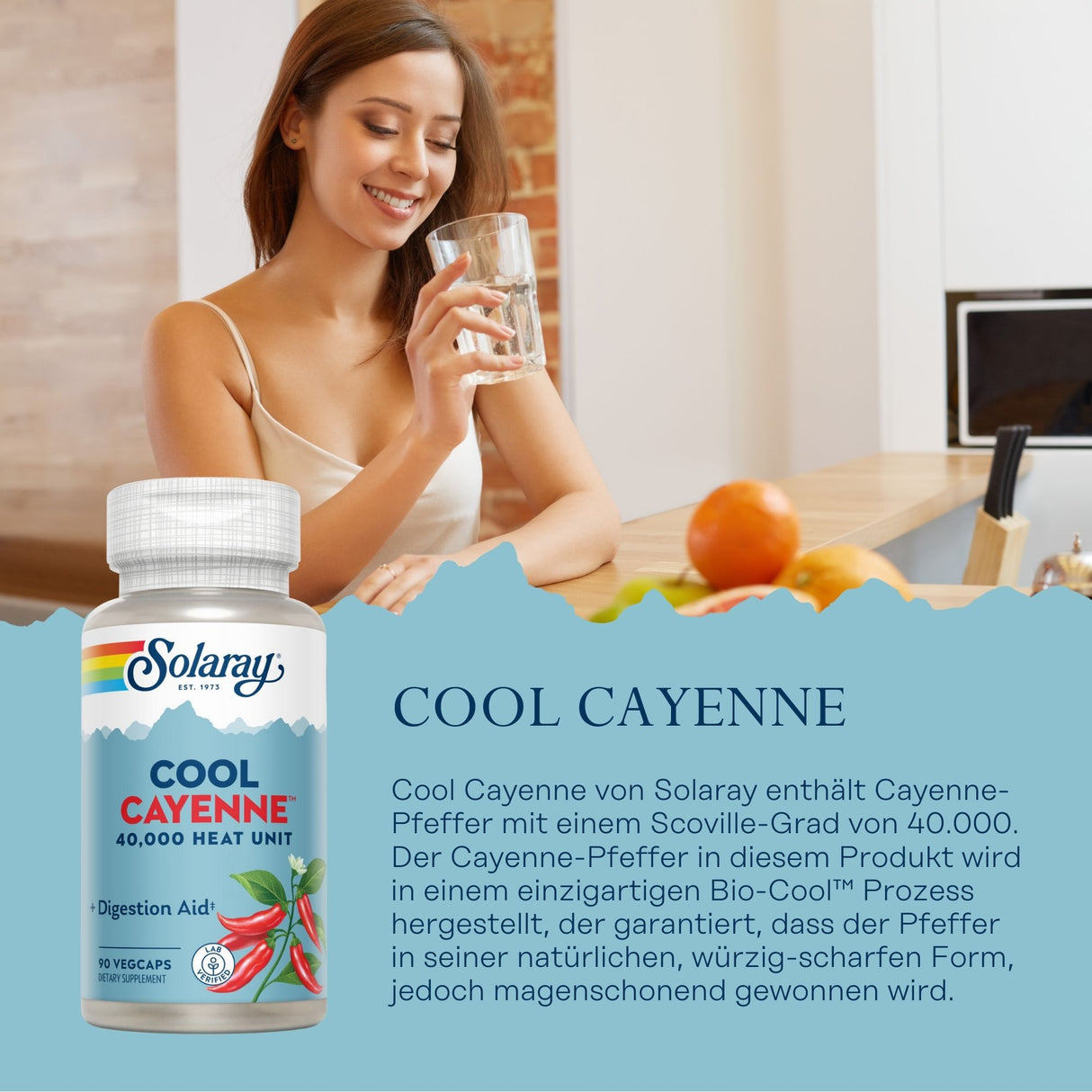 Eine Frau sitzt an einem Holztisch in einer Küche und hält ein Glas Wasser. Vor ihr steht eine Flasche des Nahrungsergänzungsmittels 'Cool Cayenne' von Solaray. Die Flasche ist mit roten Cayenne-Pfeffern und dem Text '40,000 Heat Unit' bedruckt. Der Hintergrund ist ein heller Raum mit einer Ziegelwand.