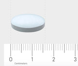 Eine weiße, runde Tablette liegt auf einer grauen Oberfläche. Darunter befindet sich ein Lineal, das in Zentimetern skaliert ist. Die Tablette hat einen Durchmesser von etwa 1,5 Zentimetern.