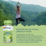 Eine Frau steht in der Yoga-Pose auf einem Bein mit erhobenen Armen vor einer bewaldeten Berglandschaft. Links im Bild ist eine Flasche mit der Aufschrift 'Solaray Nopal Prickly Pear Cactus 500 mg' zu sehen. Der Hintergrund zeigt einen bewaldeten See und Berge. Text im Bild beschreibt die Vorteile von Feigenkaktus als Nahrungsergänzungsmittel.