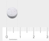 Das Bild zeigt eine weiße Tablette mit roten Flecken, die auf einem Lineal liegt. Das Lineal hat eine Skala in Zentimetern und Millimetern. Die Tablette liegt bei etwa 1,5 Zentimetern auf der Skala.