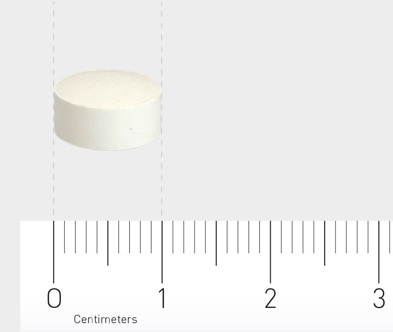 Das Bild zeigt eine weiße, runde Tablette, die auf einem Lineal mit Zentimeterangaben liegt. Die Tablette ist etwa 1 Zentimeter im Durchmesser. Der Hintergrund ist neutral und hellgrau.