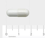 Eine weiße Kapsel liegt horizontal auf einem Lineal mit Zentimeter-Maßeinheiten, das den Maßstab zeigt. Der Hintergrund ist grau.