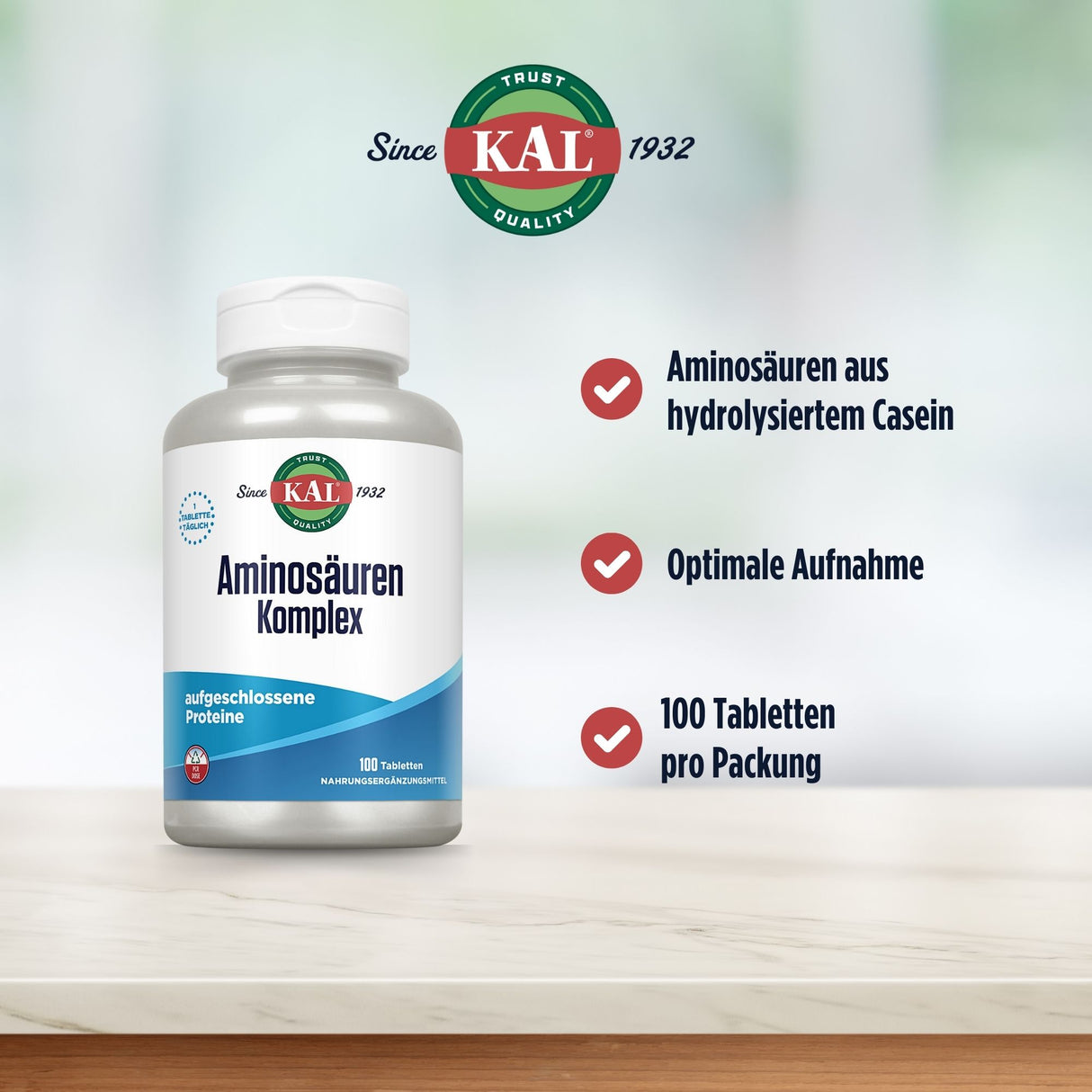 Das Bild zeigt eine Produktverpackung von KAL Aminosäuren Komplex auf einem hellen Untergrund. Links im Bild steht eine weiße Flasche mit blauem Etikett, auf dem 'Aminosäuren Komplex' und 'aufgeschlossene Proteine' steht. Rechts daneben befinden sich drei rote Häkchen mit den Texten: 'Aminosäuren aus hydrolysiertem Casein', 'Optimale Aufnahme', '100 Tabletten pro Packung'. Oben ist das KAL-Logo mit der Aufschrift 'Since 1932'. Der Hintergrund ist unscharf und hell.