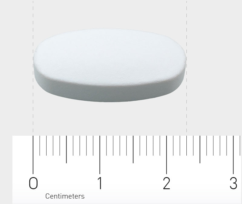 Das Bild zeigt eine weiße, ovale Tablette, die auf einem Lineal liegt. Das Lineal ist in Zentimetern skaliert und zeigt, dass die Tablette etwa 2 Zentimeter lang ist. Der Hintergrund ist einfarbig hellgrau.