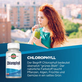 Eine Frau mit roten Haaren trinkt aus einem Glas mit grünem Getränk, möglicherweise Chlorophyll, auf einer städtischen Terrasse. Im Hintergrund sind unscharfe Gebäude zu sehen. Auf der linken Seite ist eine Verpackung mit der Aufschrift 'Chlorophyll' abgebildet.