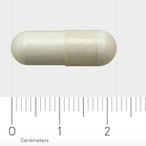 Eine weiße Kapsel liegt horizontal auf einem Lineal, das in Zentimetern skaliert ist. Die Kapsel ist etwa 2 Zentimeter lang.