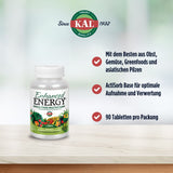 Das Bild zeigt eine weiße Plastikflasche mit dem Aufdruck 'Enhanced Energy Whole Food Multivitamin' auf einer hellen Oberfläche. Links oben ist ein Logo mit der Aufschrift 'Since 1932 KAL Trust Quality'. Rechts neben der Flasche sind drei rote Häkchen mit Text: 'Mit dem Besten aus Obst, Gemüse, Greenfoods und asiatischen Pilzen', 'ActiSorb Base für optimale Aufnahme und Verwertung', '90 Tabletten pro Packung'. Der Hintergrund ist unscharf und in hellgrünen Tönen gehalten.