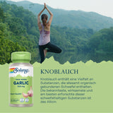 Frau in Yoga-Position vor See und Wald. Solaray Knoblauch-Kapseln im Vordergrund. Text erklärt gesundheitliche Vorteile von Allicin in Knoblauch.