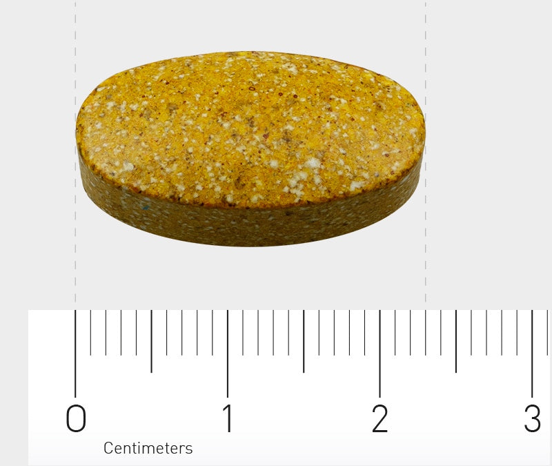 Das Bild zeigt eine ovale, gelbe Tablette mit gesprenkelter Oberfläche auf einem Lineal. Die Tablette misst etwa 2,5 cm in der Länge. Das Lineal ist in Zentimetern markiert und zeigt die Größe der Tablette an. Der Hintergrund ist neutral und grau.