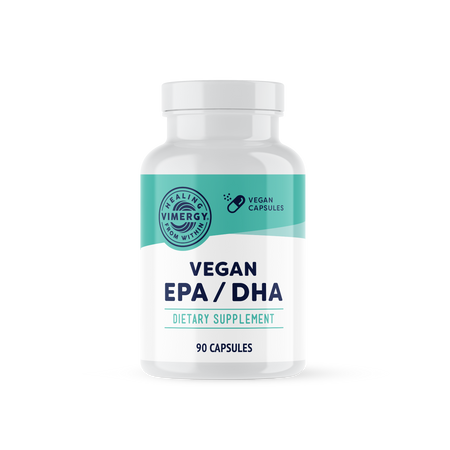 Zwei Frauen sitzen auf einem Sofa und lachen, während sie Tassen halten. Im Vordergrund ist eine Packung veganes EPA/DHA von Vimergy zu sehen. Der Text beschreibt das Produkt als fischfreie Omega-3-Fettsäuren auf Algenbasis, frei von Carrageen, Zitronensäure und künstlichen Aromen.