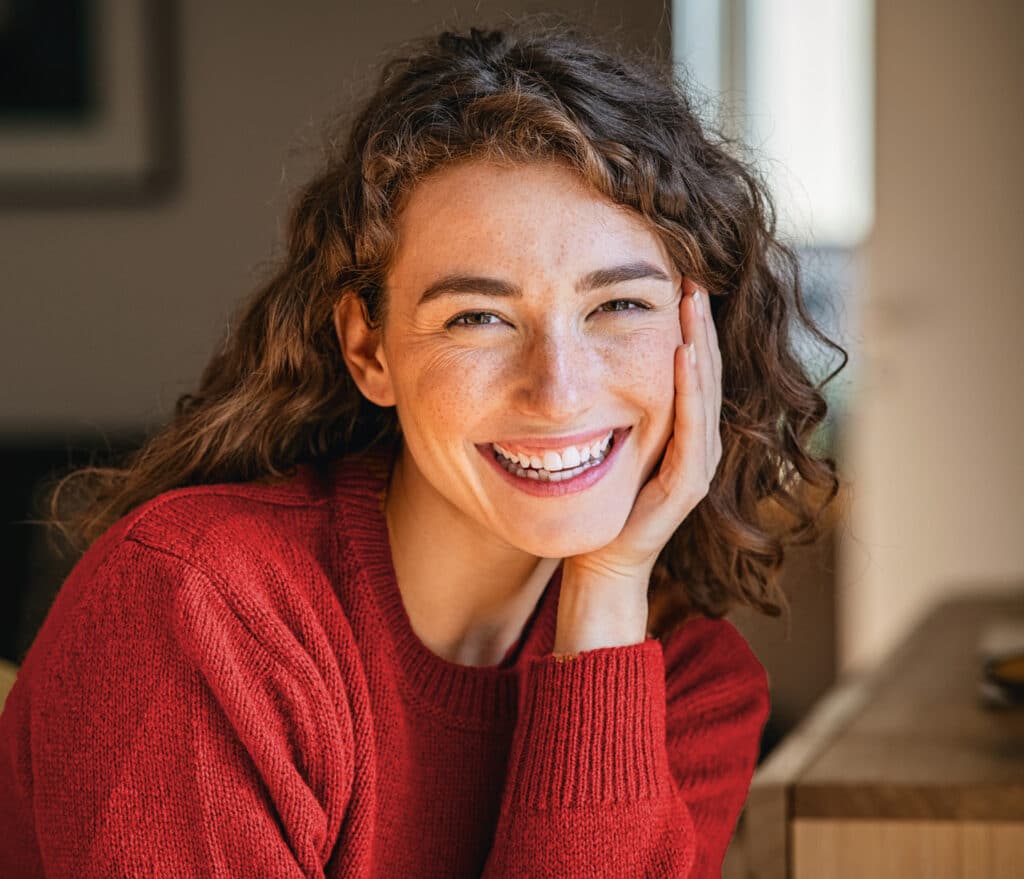 freudig lächelnde junge Frau mit rotem Wollpullover