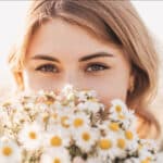 junge Frau genießt den Duft frischer Kamillenblüten