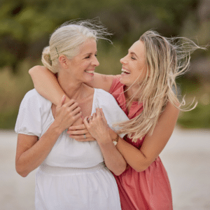 Mutter und Tochter lachen bei einem Spaziergang am Strand