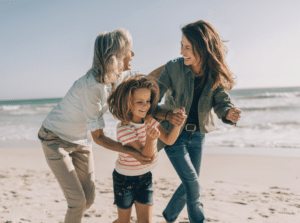 Mutter, Kind und Oma lachen bei einem Spaziergang am Strand